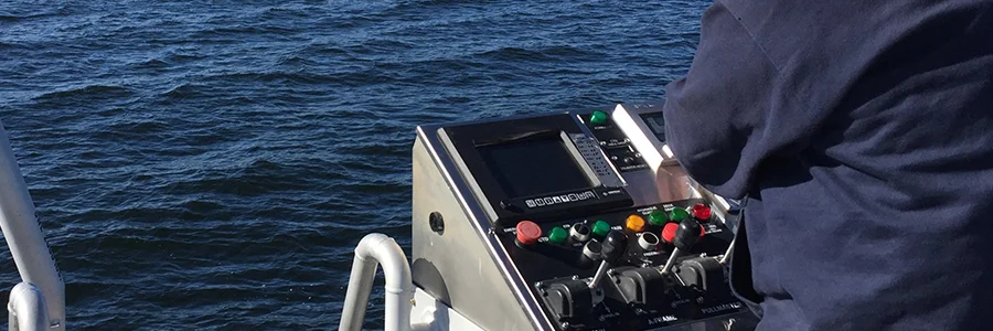A man looking at a VarTech Systems' operator interface monitor on a boat