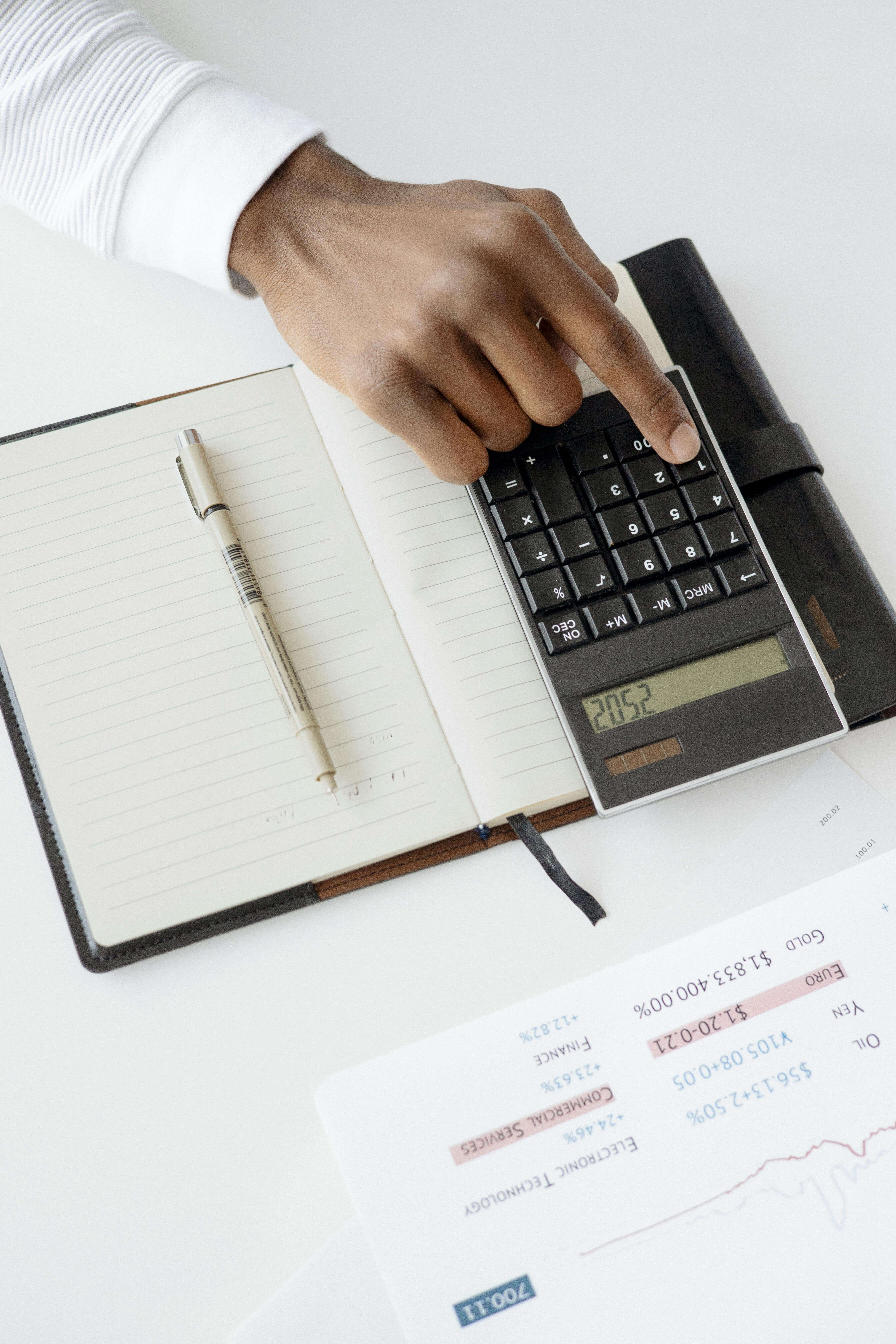 Main sur une calculatrice à côté d'un relevé et d'un carnet