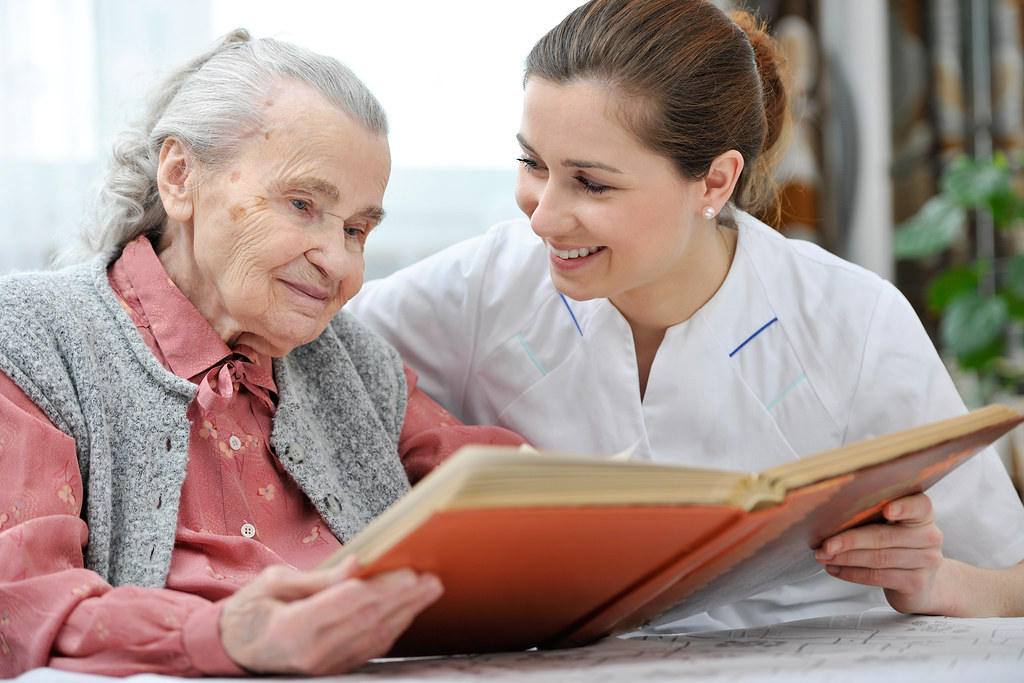 Care assistant reading with an elderly person