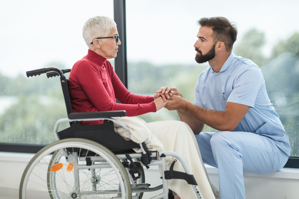 Caregiver holding the hand of an elderly person in a wheelchair