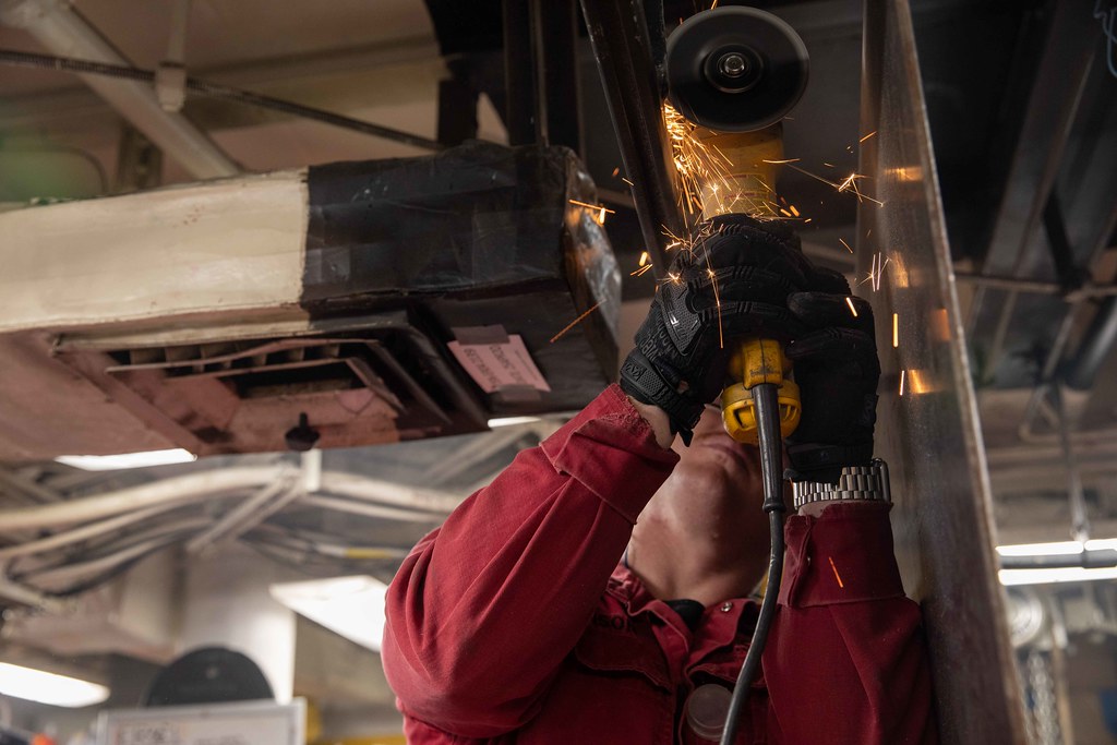 Technicien perçant une pièce métallique, gerbe d'étincelles