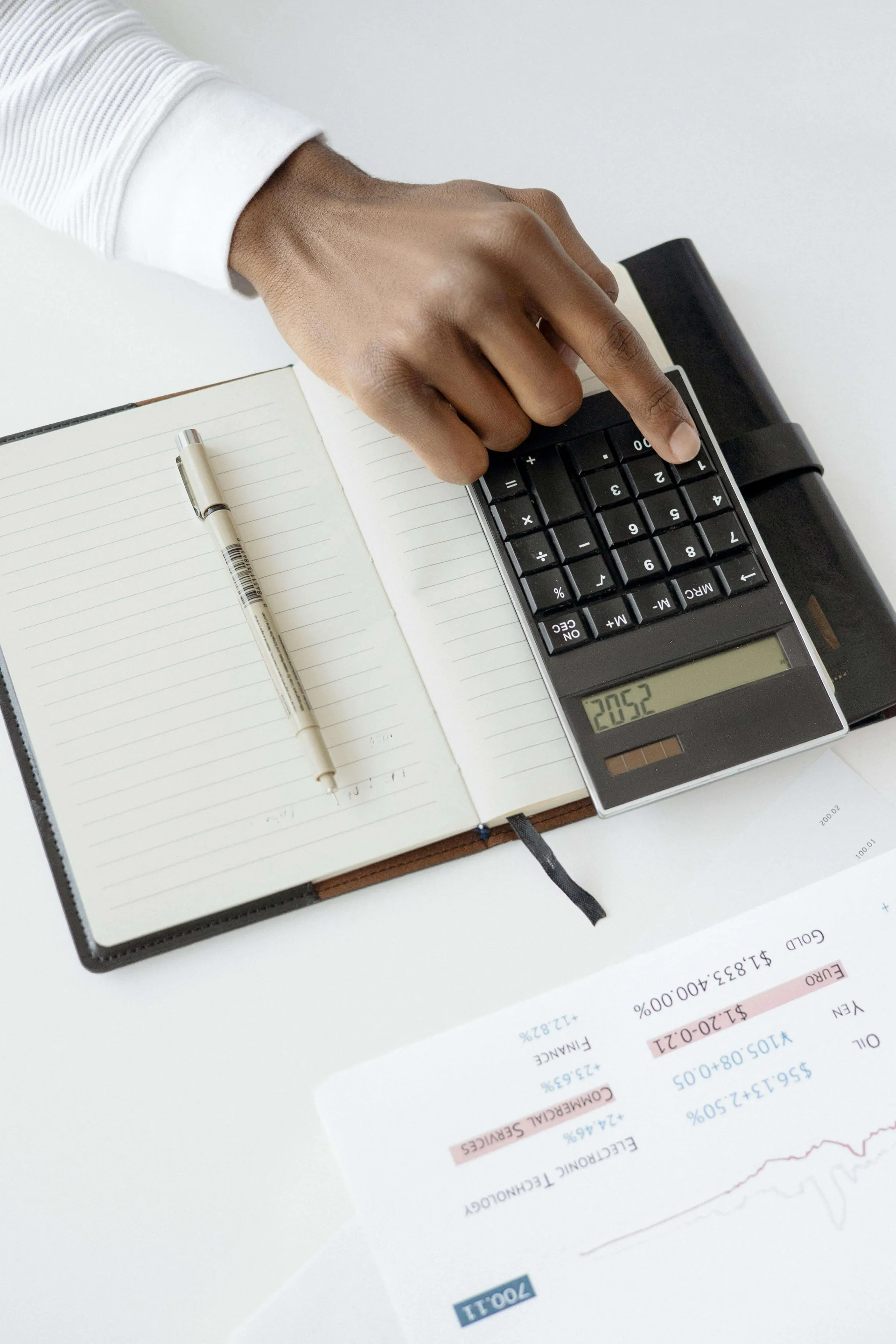 Main sur une calculatrice à côté d'un relevé et d'un carnet