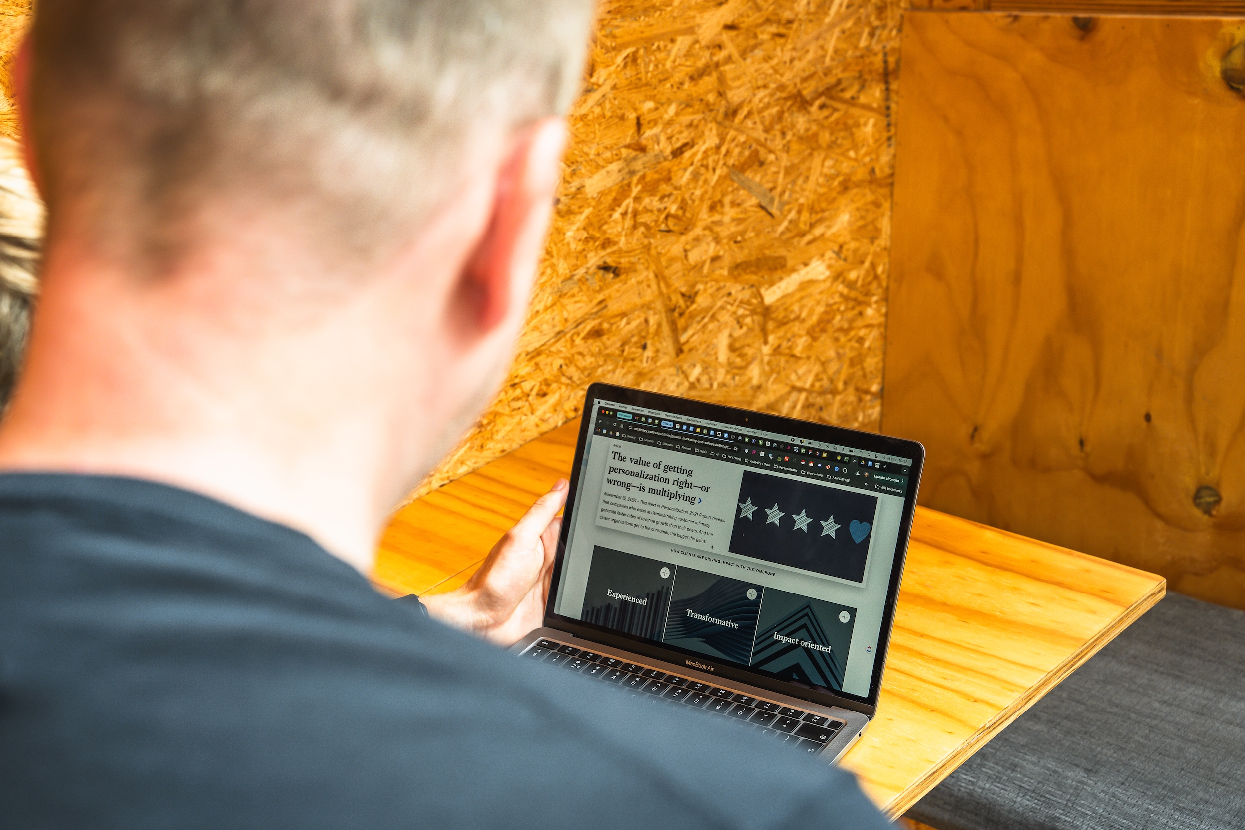 Persoon die een artikel leest over het belang van personalisatie op een laptop in houtachtige werkomgeving.