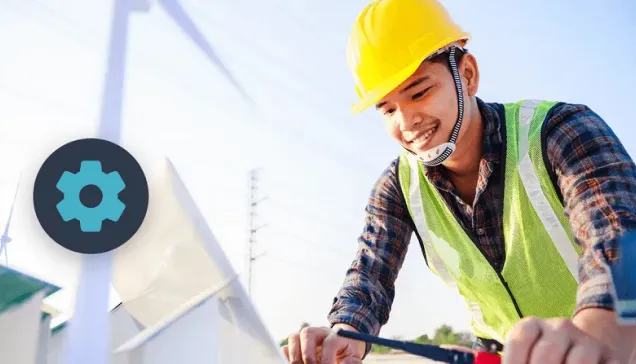 Construction worker wearing a yellow hard hat and safety vest smiling while working outdoors.