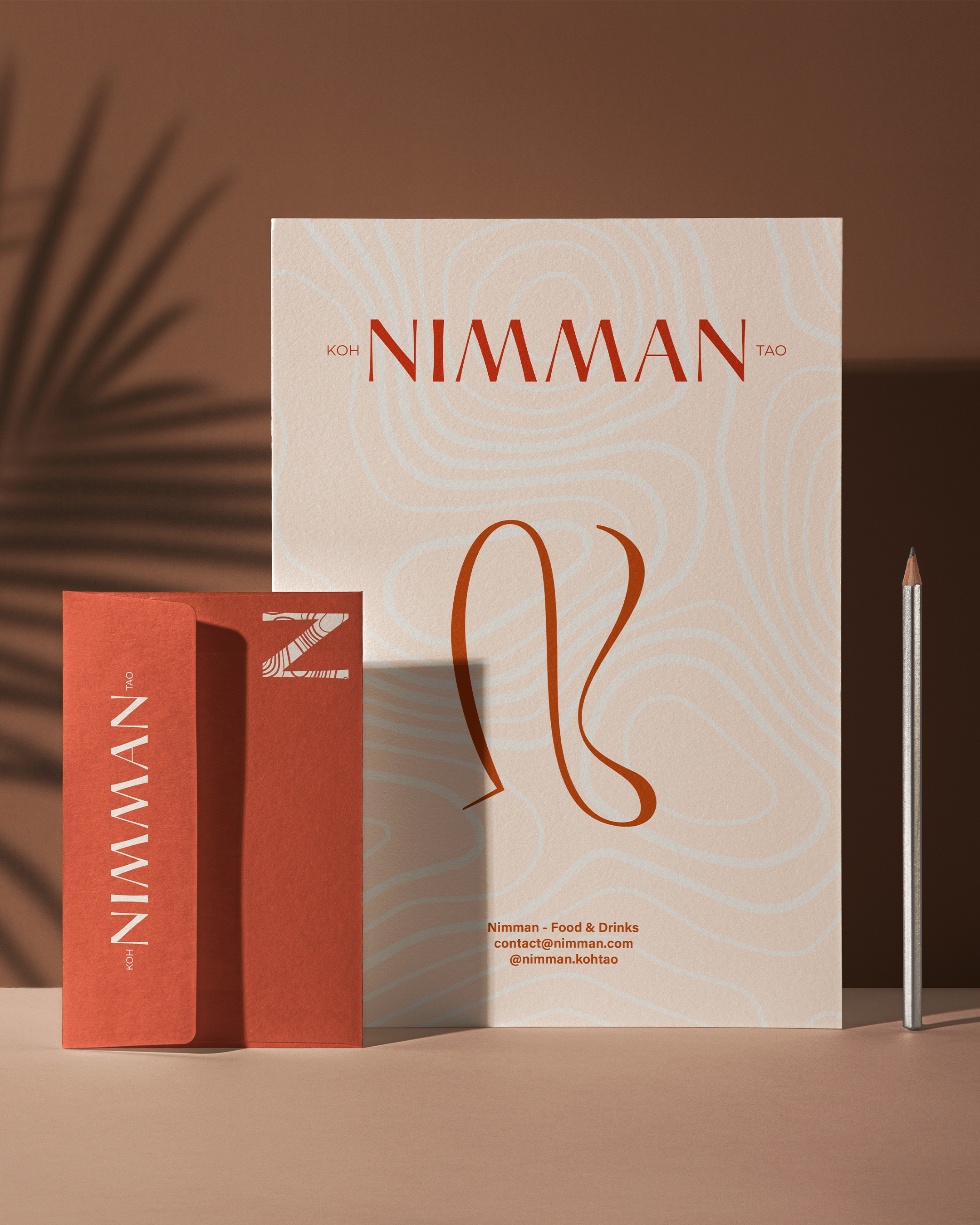 Papeterie élégante avec carte et enveloppe couleur terre cuite sur fond beige, marquée 'Nimman Koh Tao' pour nourriture et boissons.