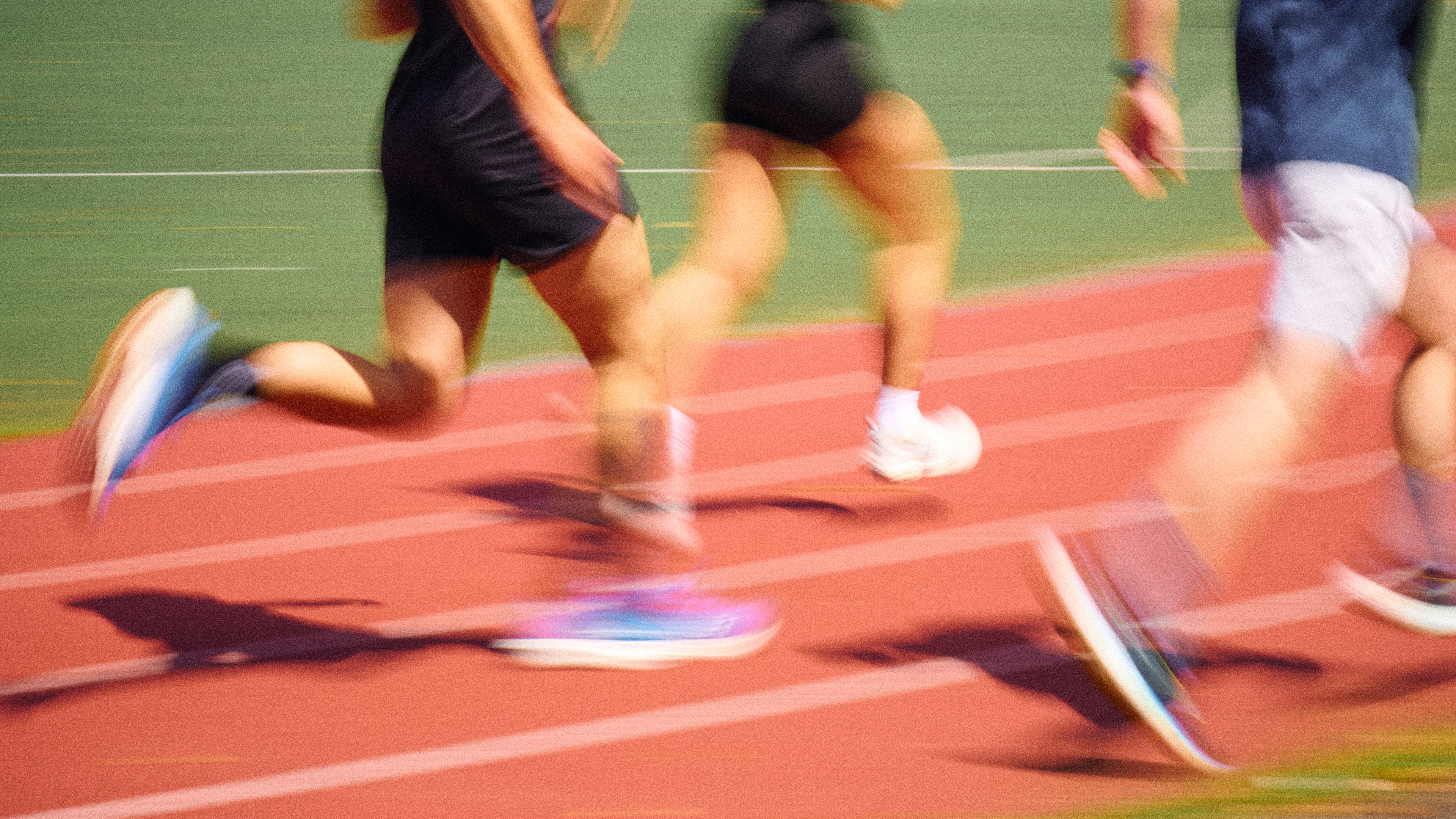 Des coureurs en tenue de sport courant rapidement sur une piste d'athlétisme rouge avec un flou de mouvement.