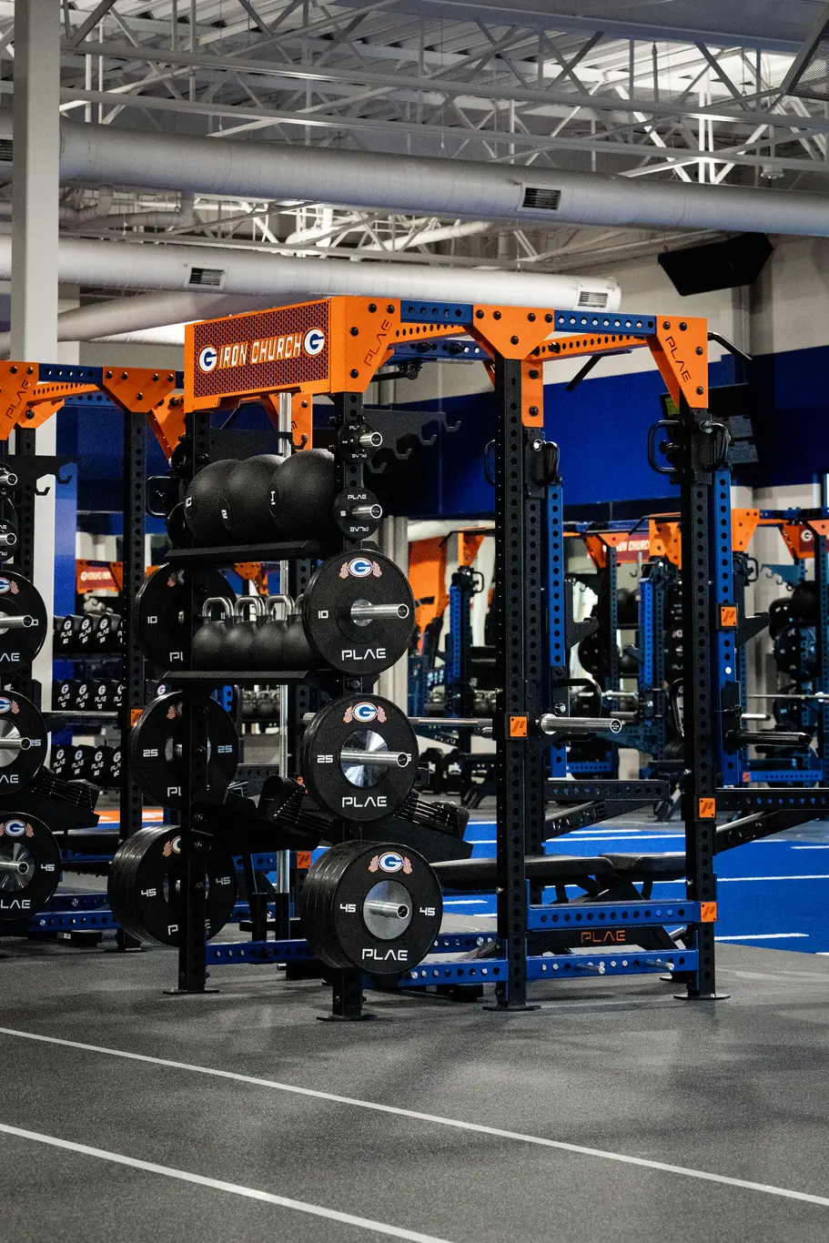 Custom branded PLAE ICONx rack featuring integrated storage, medicine balls, kettlebells and branded weight plates.
