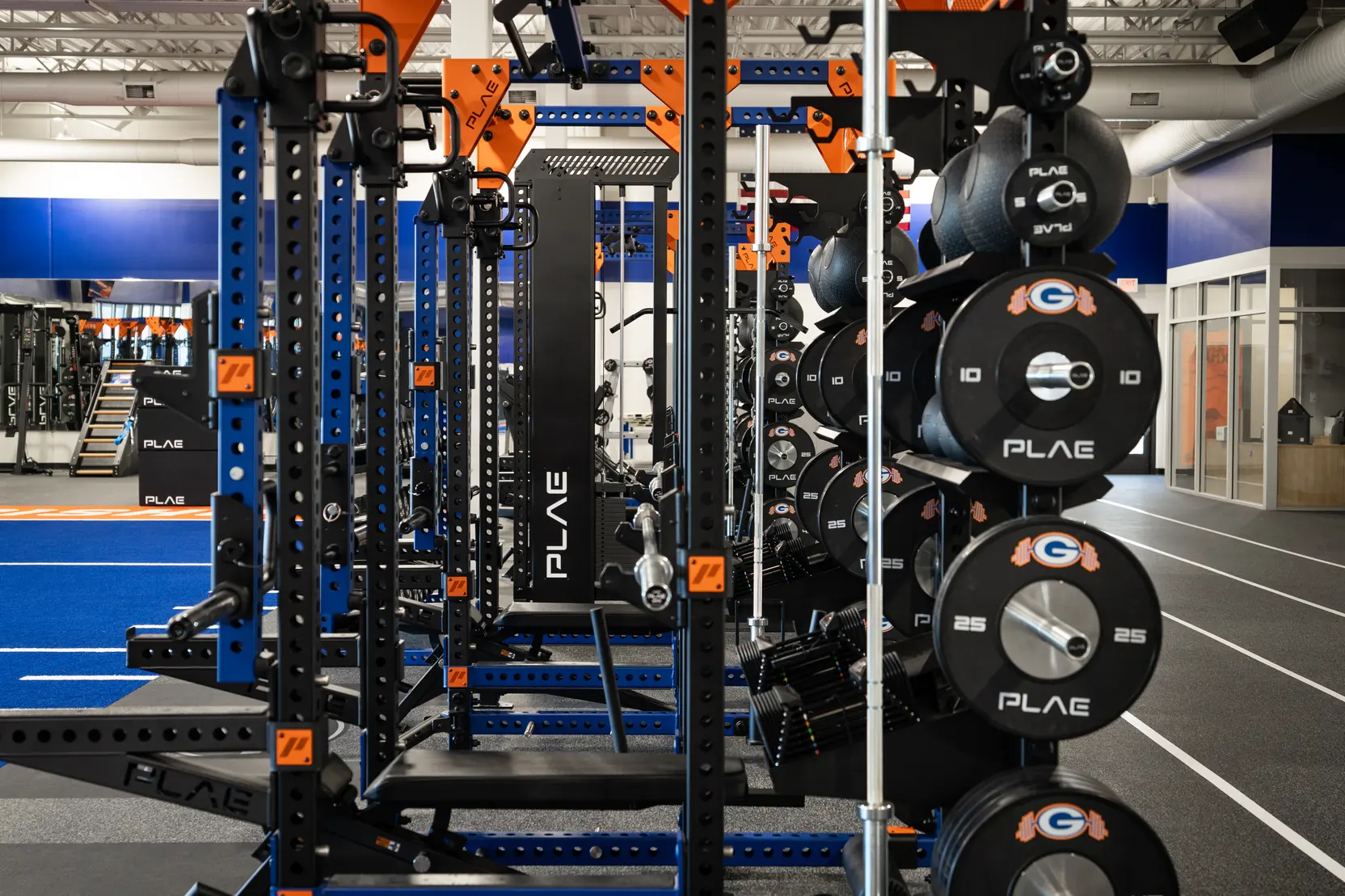Side profile of custom branded PLAE ICONx racks with integrated weight storage and strength training accessories.