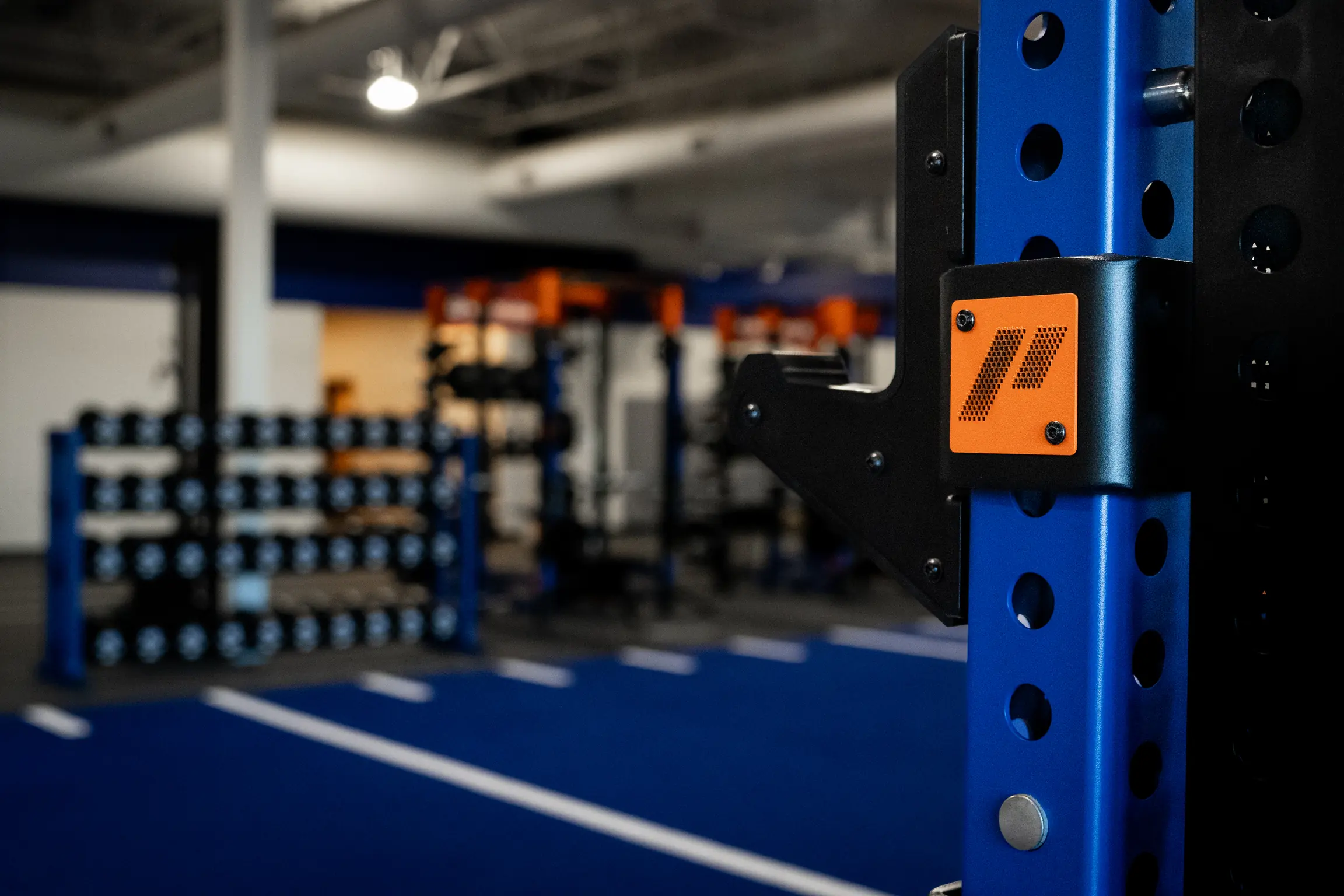 Detail of a custom PLAE ICONx rack attachment within a branded collegiate strength training facility.