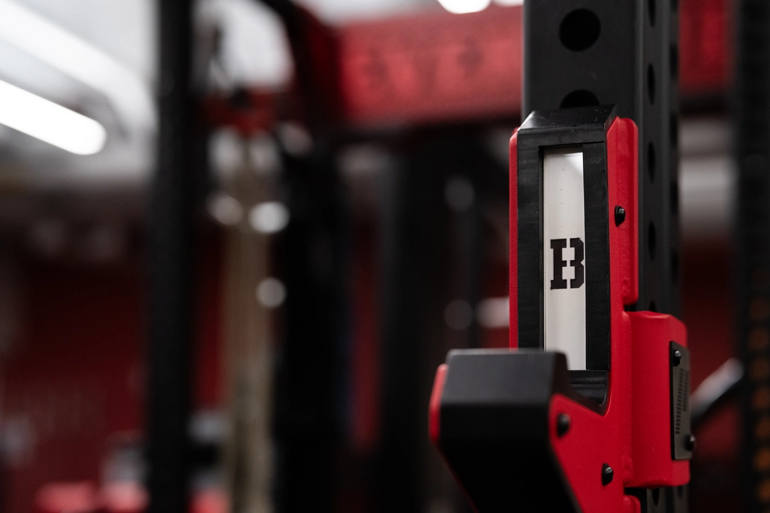 Close-up of a custom PLAE J-cup with Brown University branding installed on a PLAE ICONx strength rack.