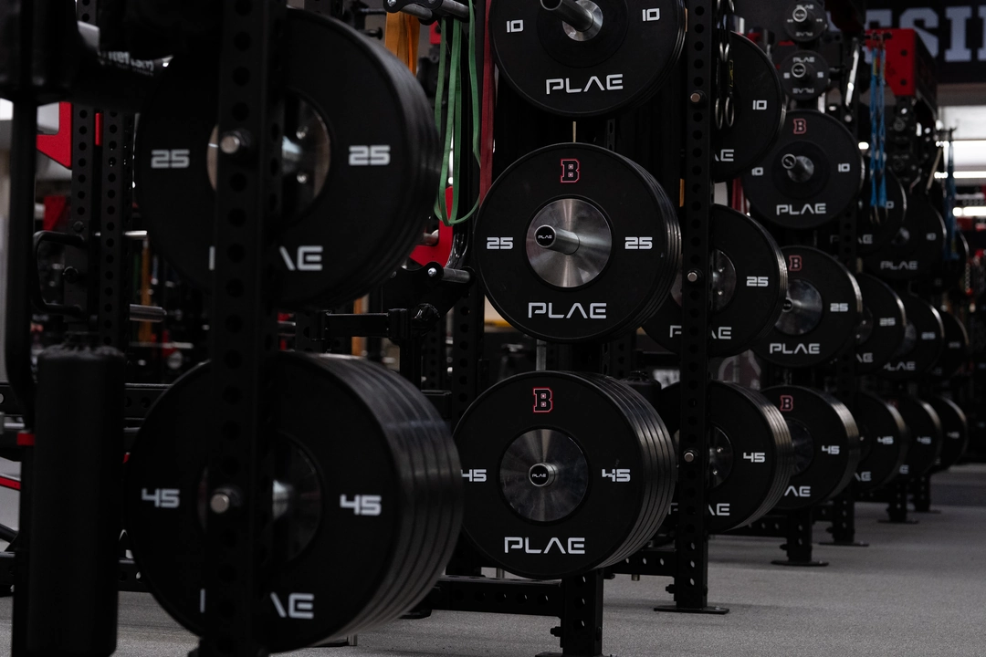 Close-up of integrated PLAE weight plate storage on custom PLAE ICONx racks with custom Brown University branded weight plates.