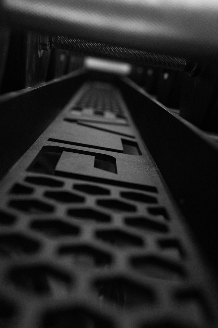 Macro detail of the custom PLAE ICONx rack nameplate showcasing precision-cut steel branding.