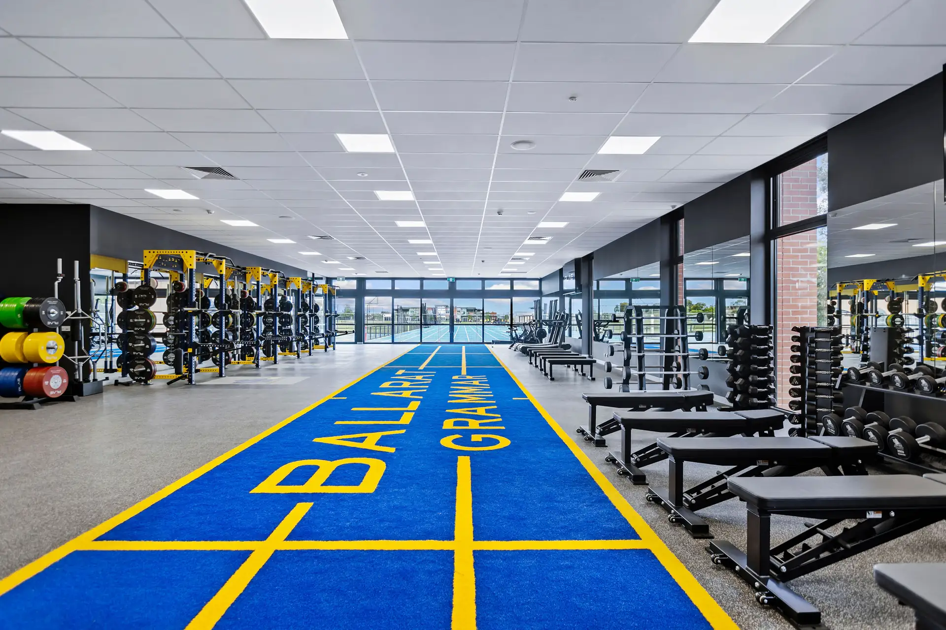Wide view of the Ballarat Grammar athletic facility with its blue-and-yellow PLAE ATTACK turf sprint track, PLAE racks, dumbbells and benches