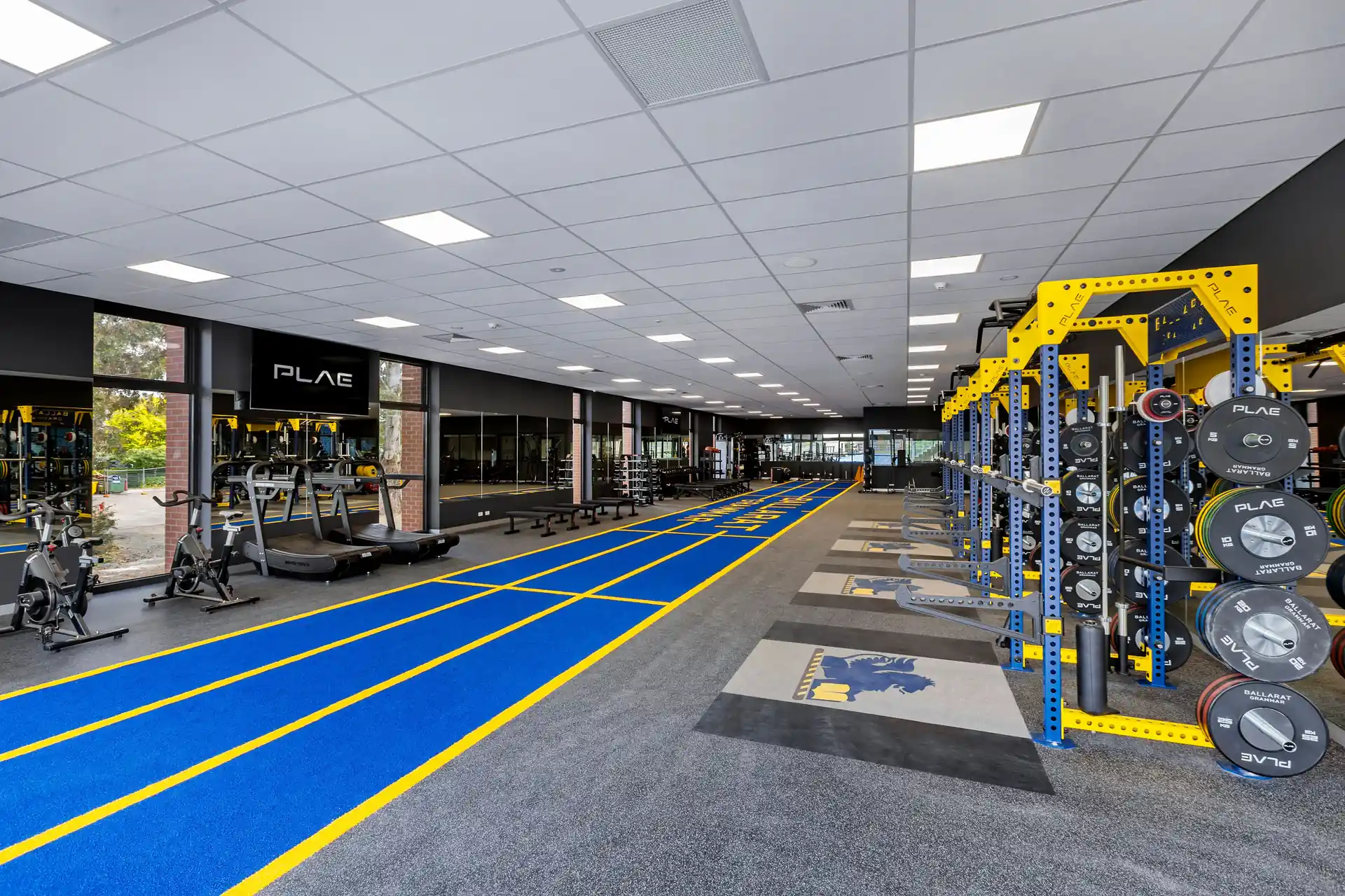 Ballarat Grammar performance gym featuring PLAE SLAT treadmills, PLAE ICON X racks with branded bumper plates and the blue ATTACK turf track