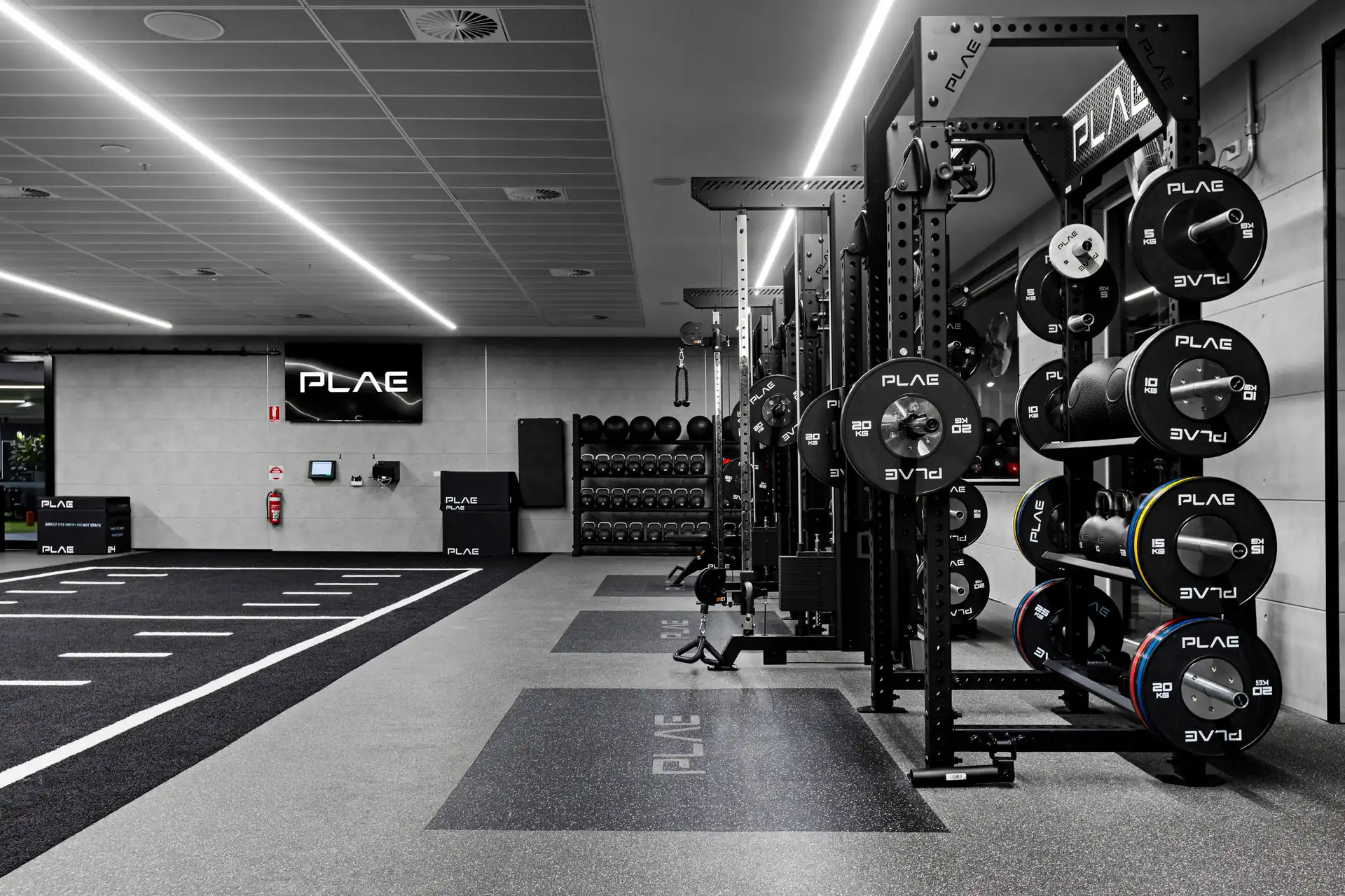 Close view of a PLAE bumper plate tree and ICON X rack with kettlebell storage on the Fitness First Richmond training floor