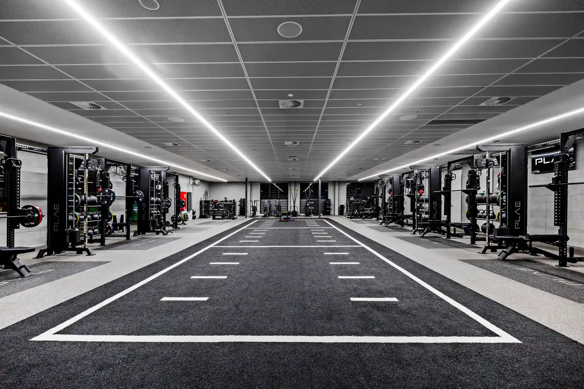 Symmetrical view of the Fitness First Richmond floor with PLAE ICON X racks flanking the central ATTACK turf sprint track