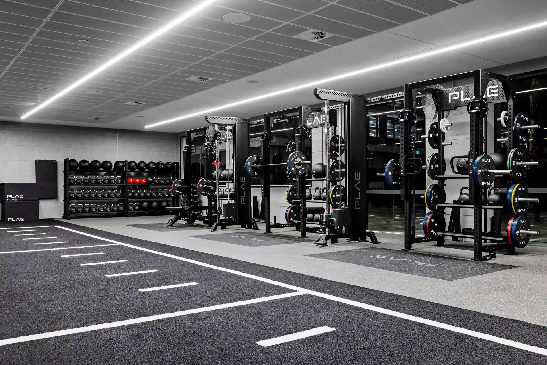 PLAE ICON X racks with calibrated bumper plate trees and slam ball storage along the ATTACK turf track at Fitness First Richmond