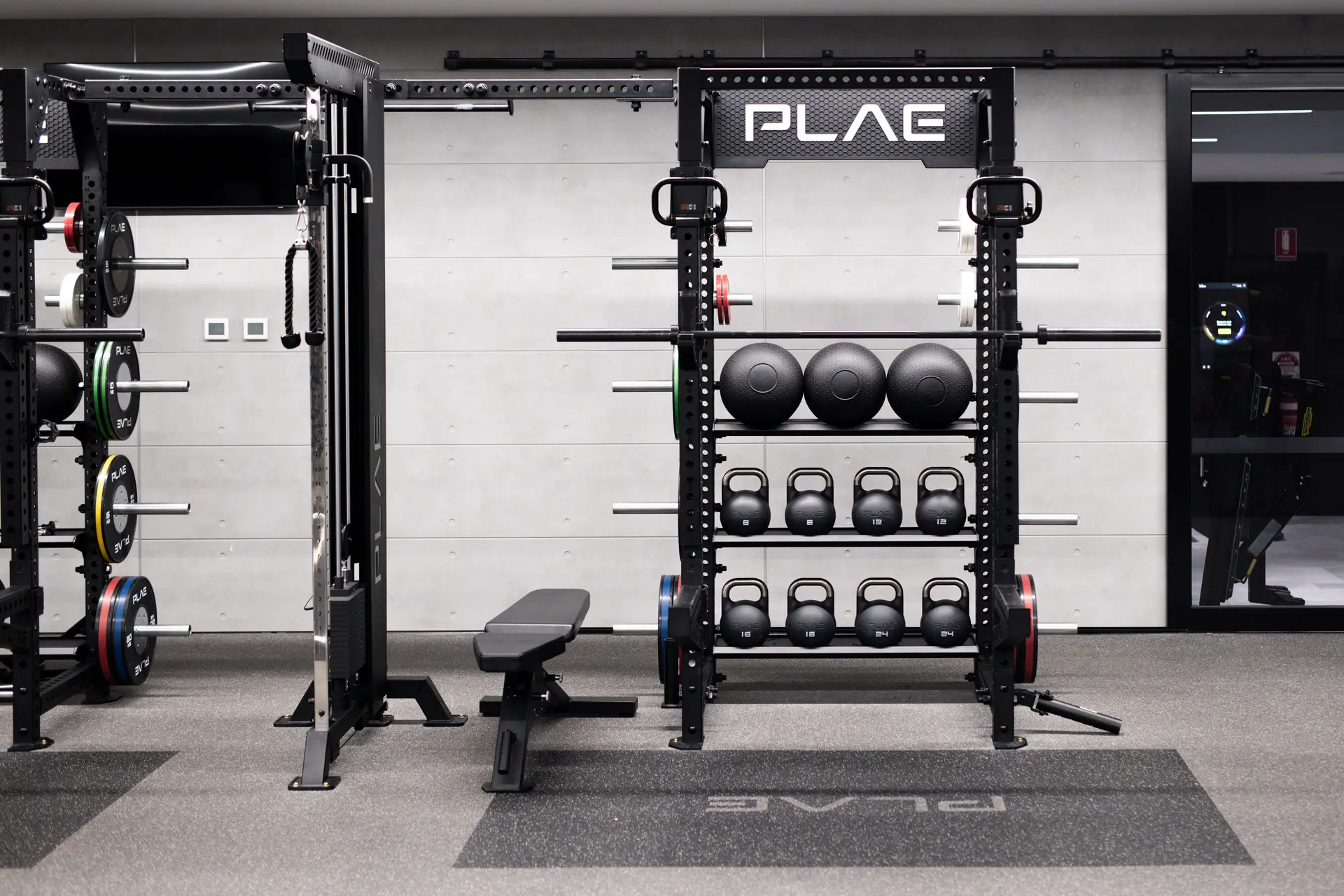 PLAE ICON X rack with slam balls, kettlebells and a cable machine beside a PLAE bench at Fitness First Richmond