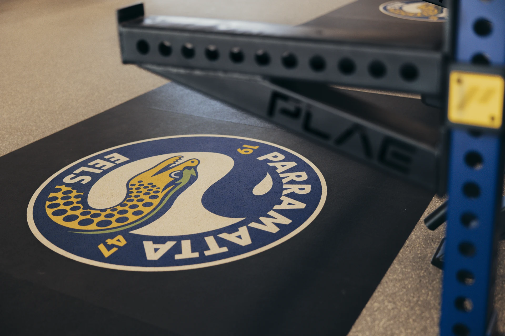 Parramatta Eels club crest inlaid into a PLAE lifting platform beside a blue ICON X rack at the Centre of Excellence