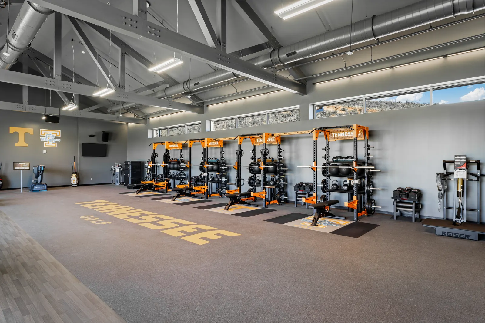 University of Tennessee golf strength facility fitted with a row of custom PLAE racks and "Tennessee Golf" performance floor graphics.