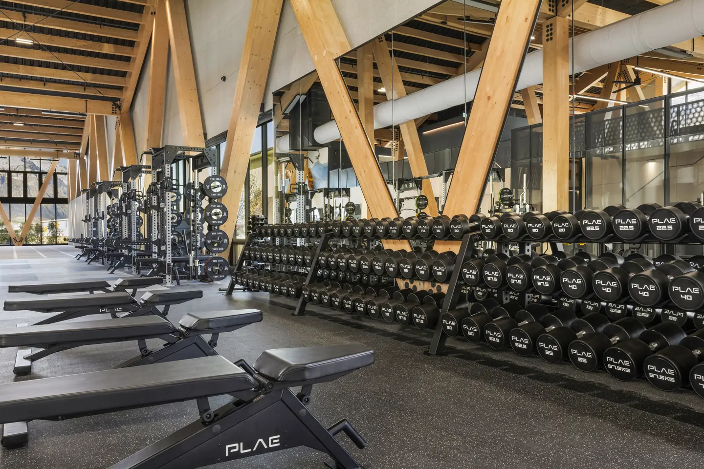 PLAE benches and tiered round dumbbells on Achieve rubber flooring beneath glulam timber trusses at The Mill, Queenstown.