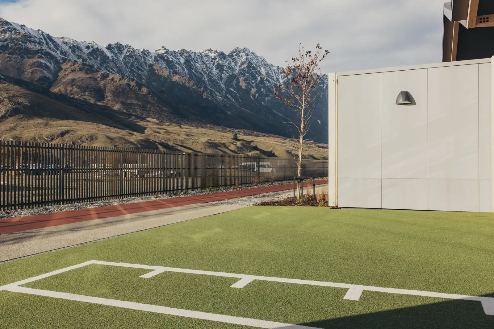Outdoor PLAE Attack turf training area at The Mill with white field markings, framed by the snow-capped Remarkables near Queenstown, New Zealand.