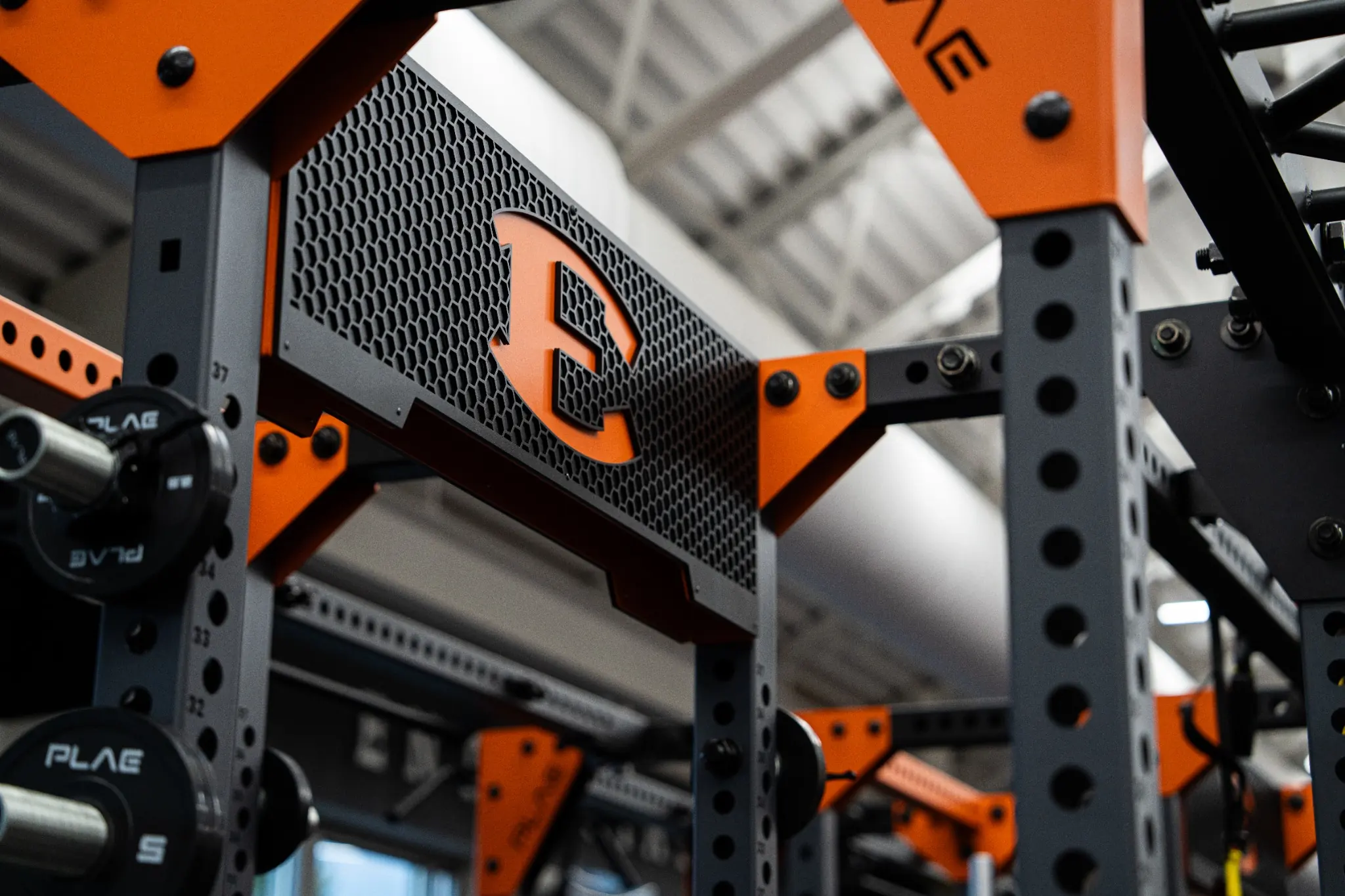 Close-up of a custom branded PLAE ICONx rack with custom grille and integrated branding in a collegiate strength facility.