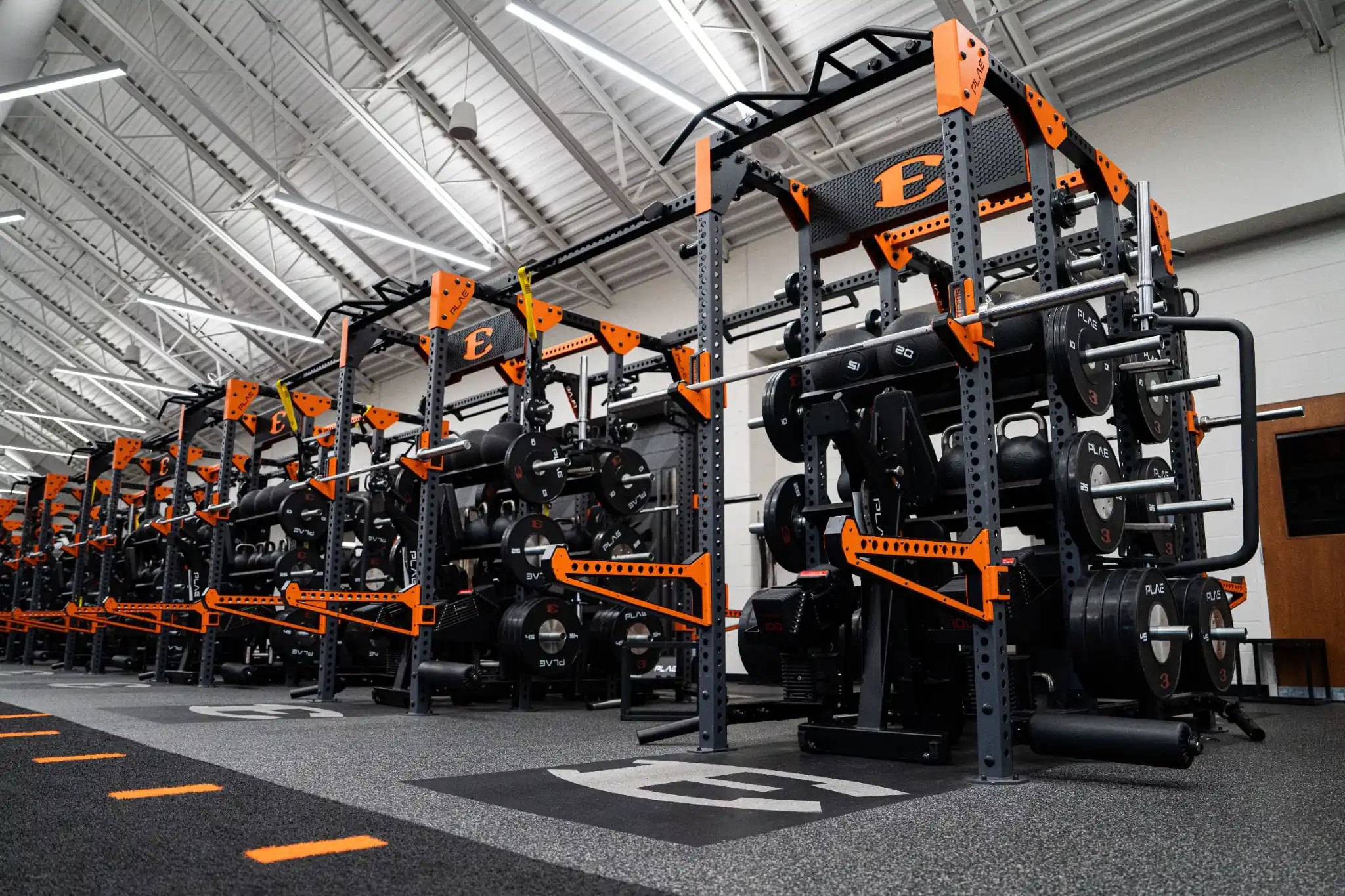 Custom branded PLAE ICONx rack line with integrated storage, ARMR equipment and Achieve rubber flooring in a high-performance weight room.