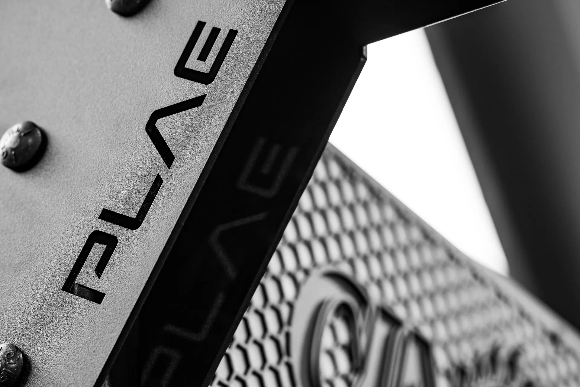 Macro detail of the PLAE ICONx rack frame showcasing premium steel construction and custom branded nameplate.
