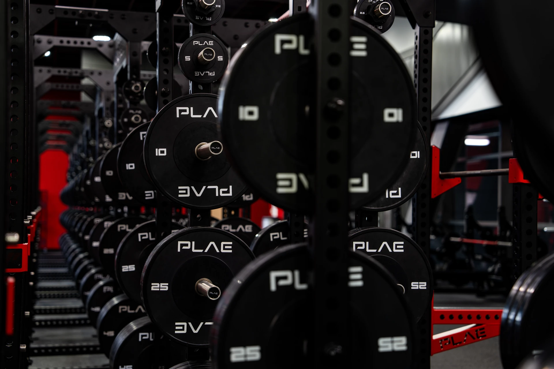 Perspective view of custom PLAE weight plate storage integrated into ICONx strength racks within a collegiate performance facility.