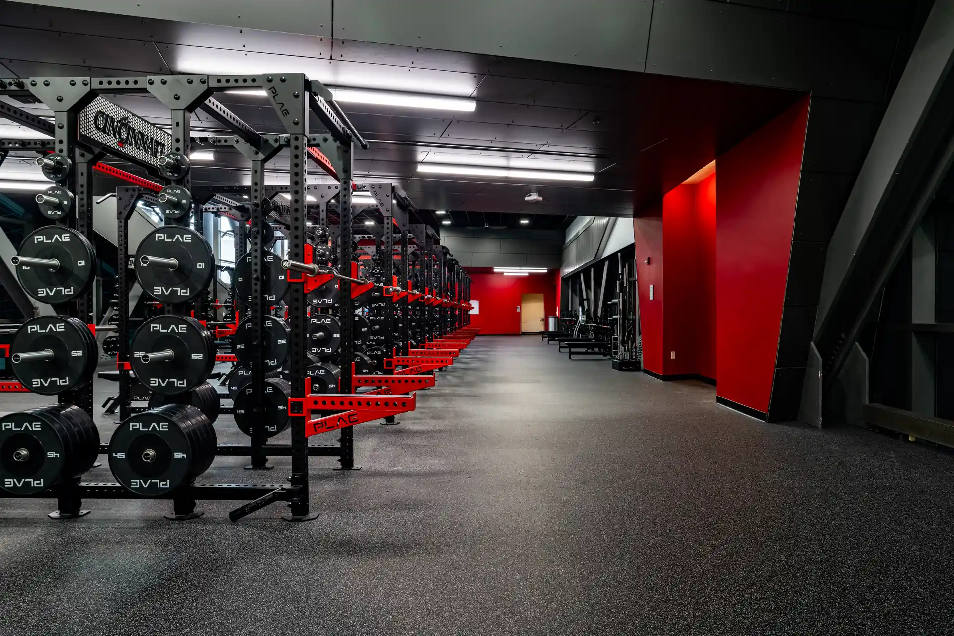 Side view of custom PLAE ICONx strength racks with integrated plate storage and lifting stations on ACHIEVE Rubber Flooring.