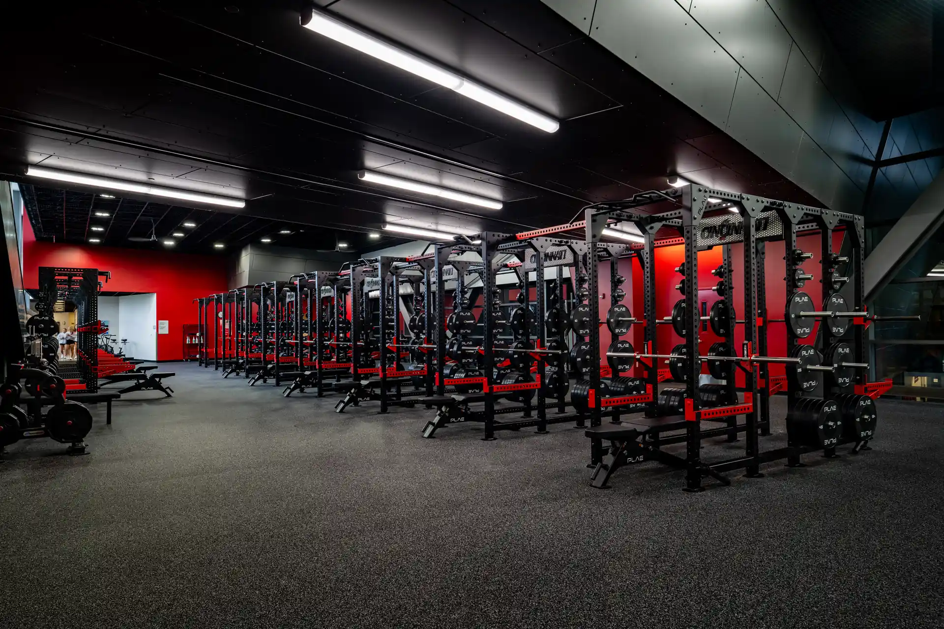 Wide-angle view of custom PLAE ICONx strength training systems with integrated benches and weight storage throughout a performance facility.