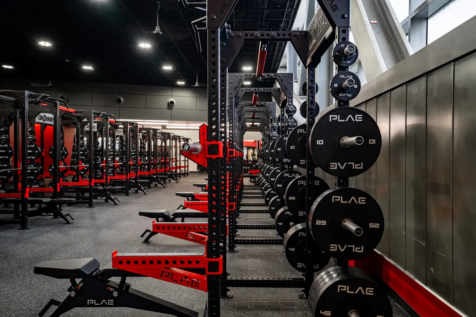 Side view of custom PLAE ICONx racks with integrated weight storage and flat benches installed on ACHIEVE Rubber Flooring.