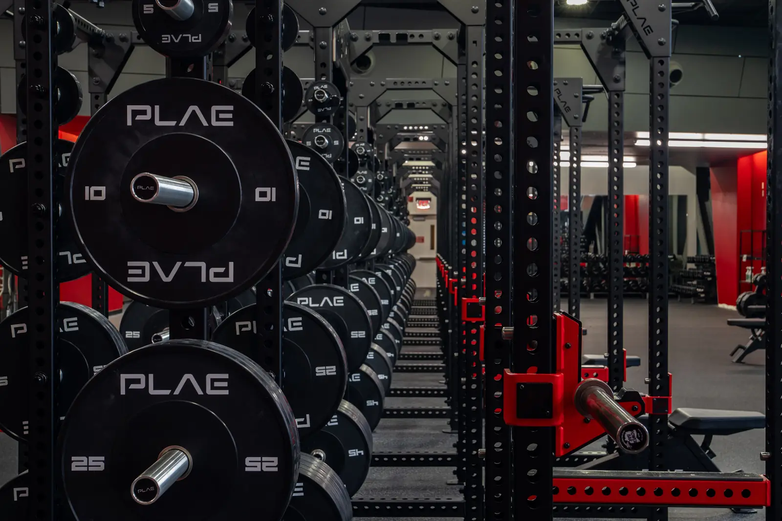 Close-up of integrated PLAE weight plate storage on custom ICONx strength racks in a collegiate training facility.