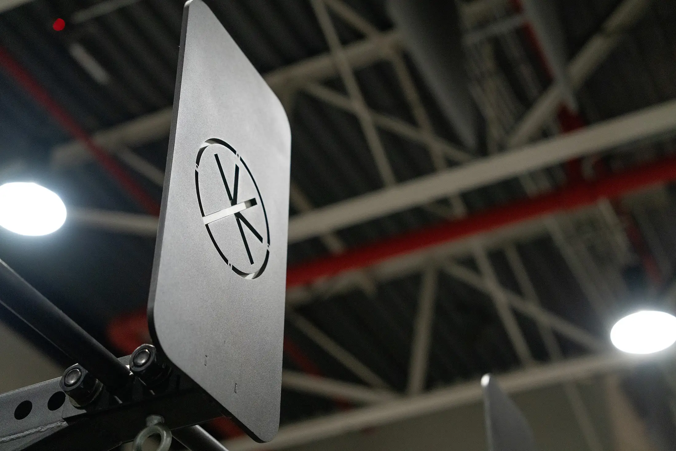 Close-up of the health club asterisk logo plate mounted on a functional rig, set against the exposed steel ceiling trusses.