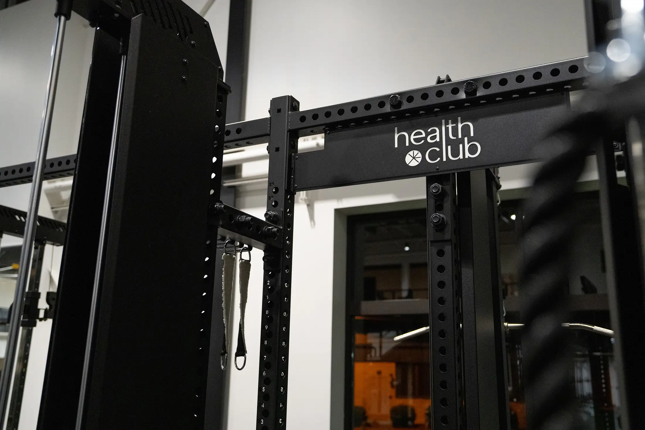 Detail of a "health club" branded PLAE-style power rack upright, showing numbered laser-cut uprights and adjustment holes.
