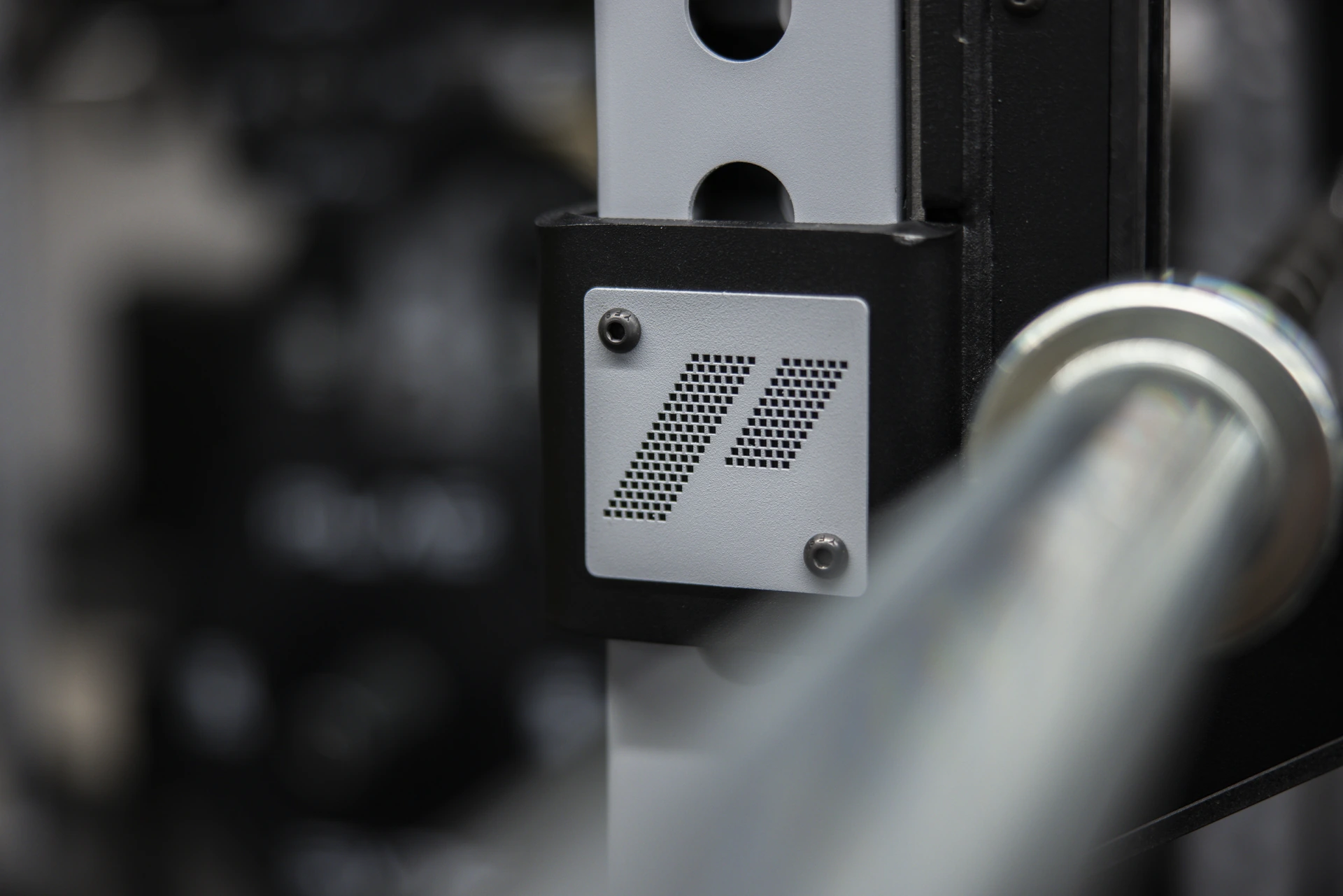 Close-up of a barbell sleeve against an ICONx upright with a PLAE branded nameplate