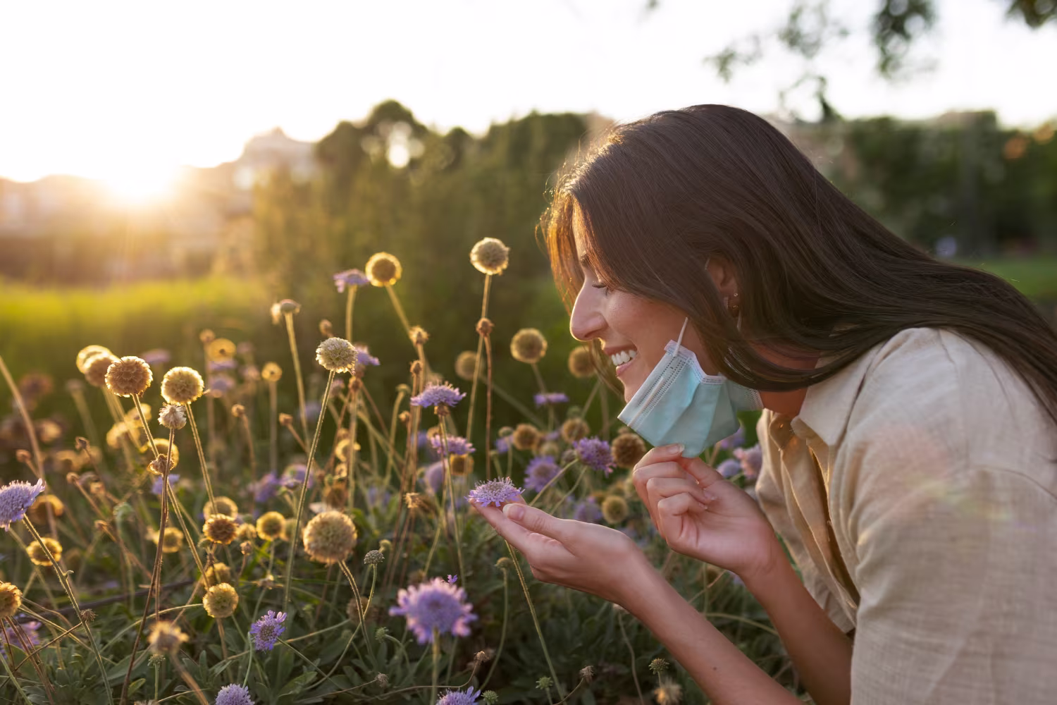 Smiley woman smelling flowers side view
