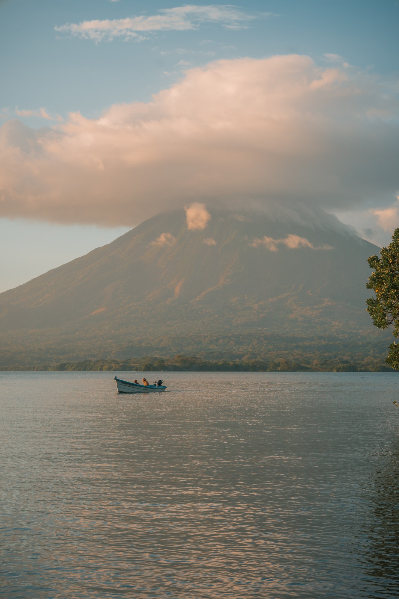 A small boat crossing Lake Nicaragua at sunrise, with Concepción volcano behind