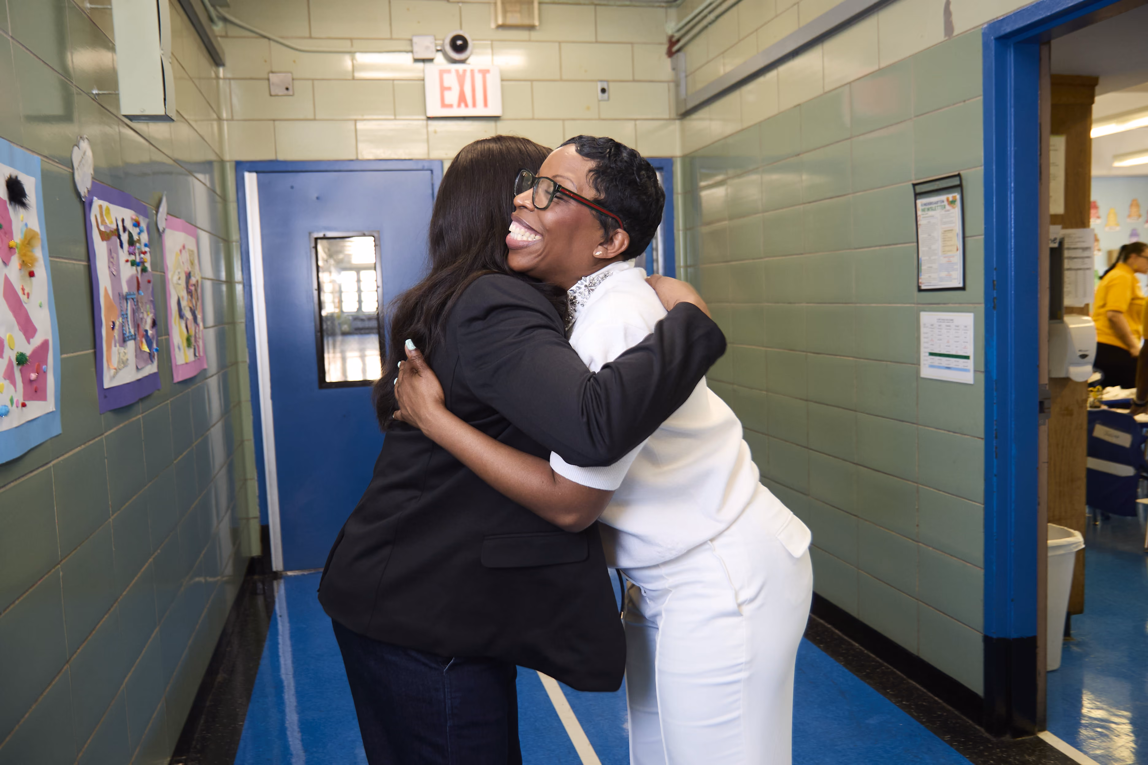 Two adults sharing a warm embrace in a school hallway