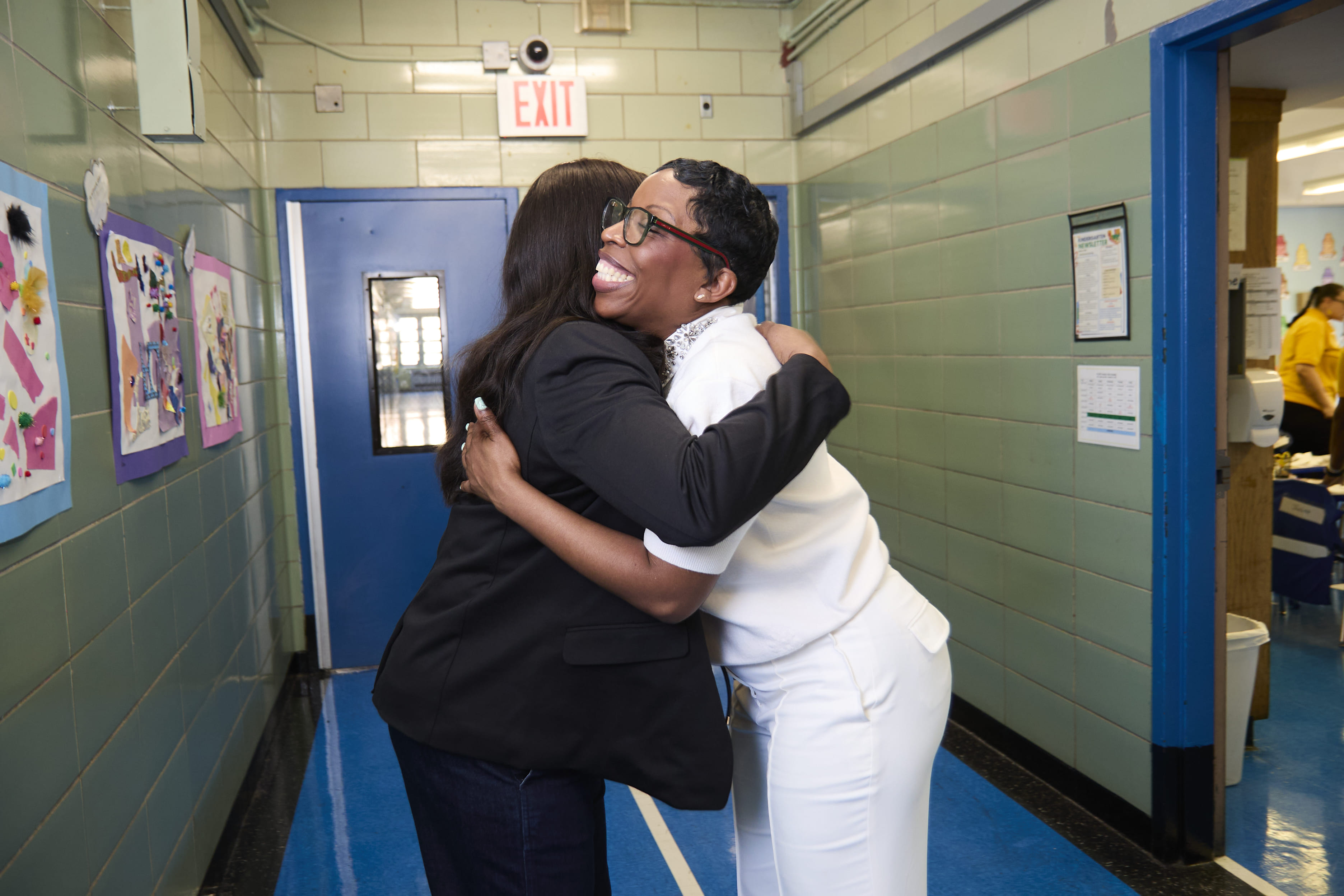 Two adults sharing a warm embrace in a school hallway