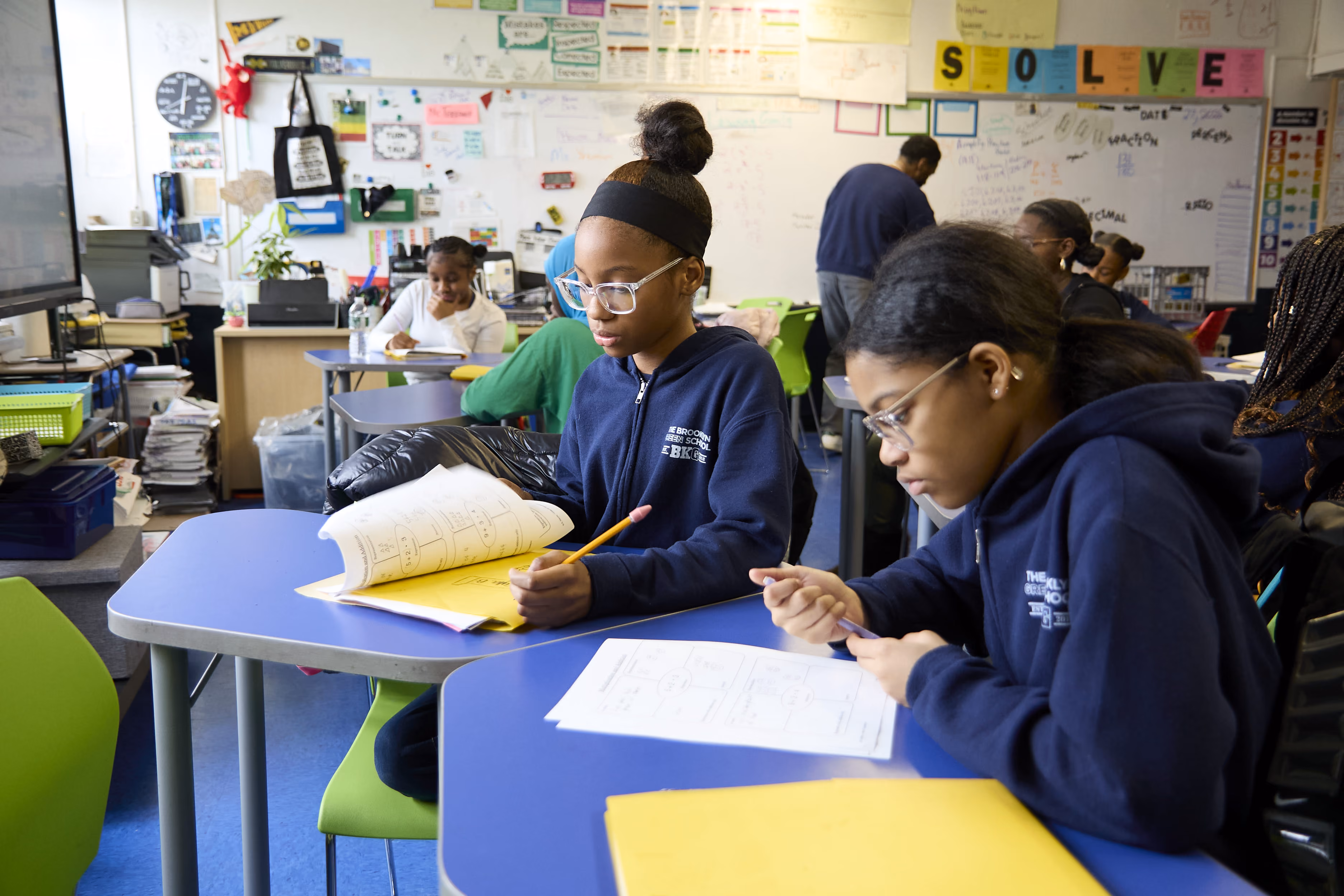 Two middle school students in uniform working on math worksheets together
