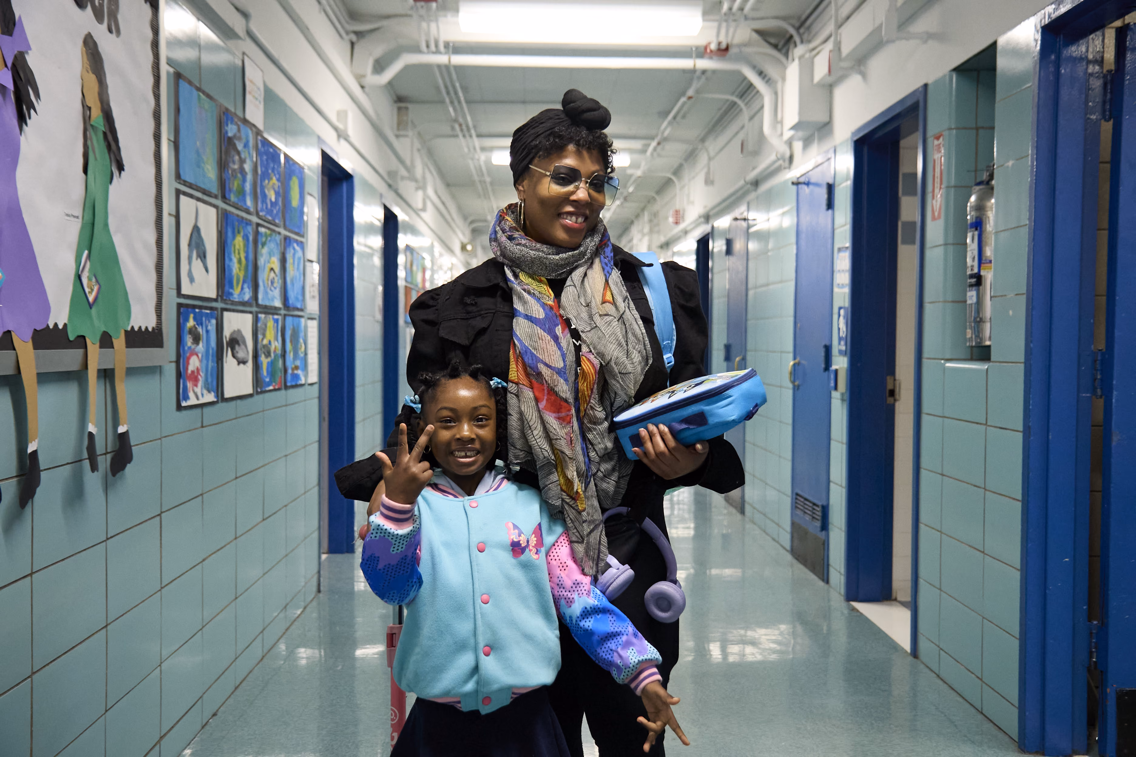 Adult and young student smiling together in school hallway