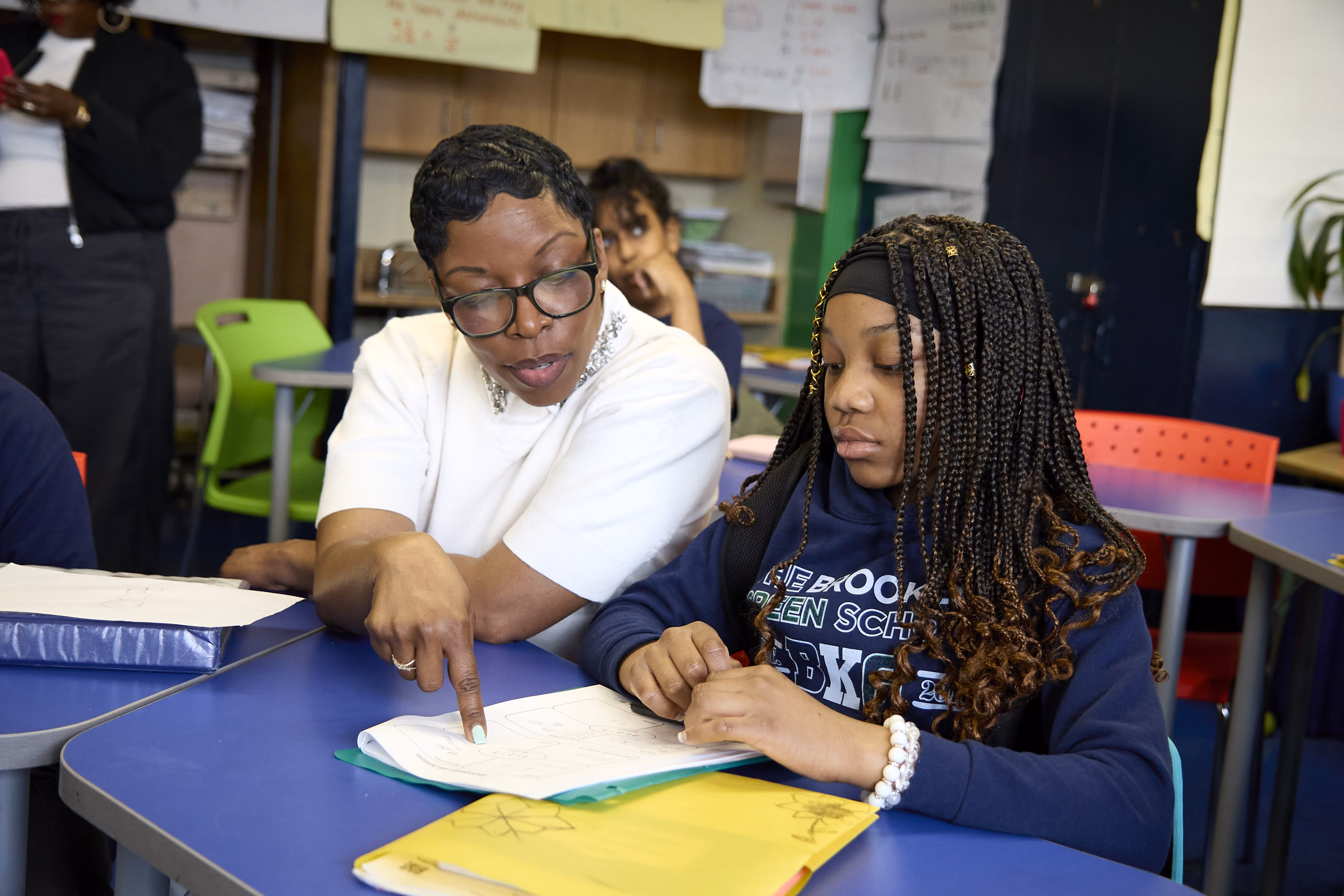 Teacher pointing at student's open notebook during classroom lesson