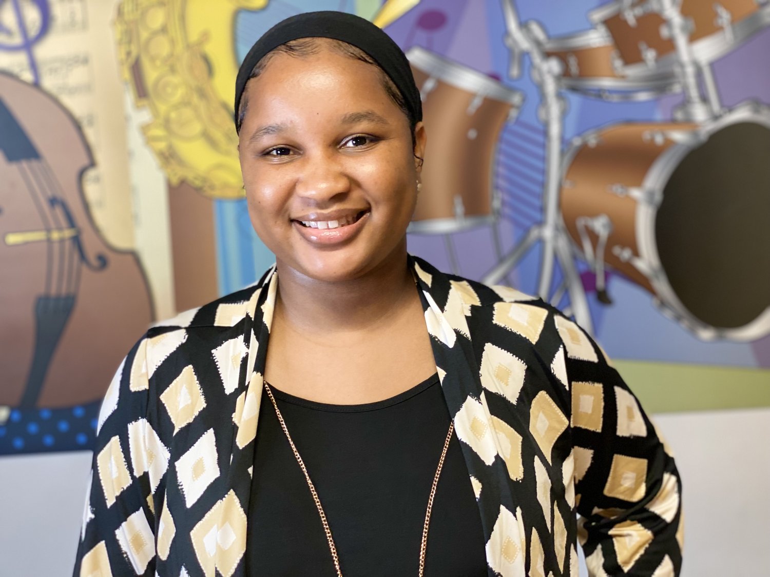 Mariem Cisse smiling in front of a music-themed mural