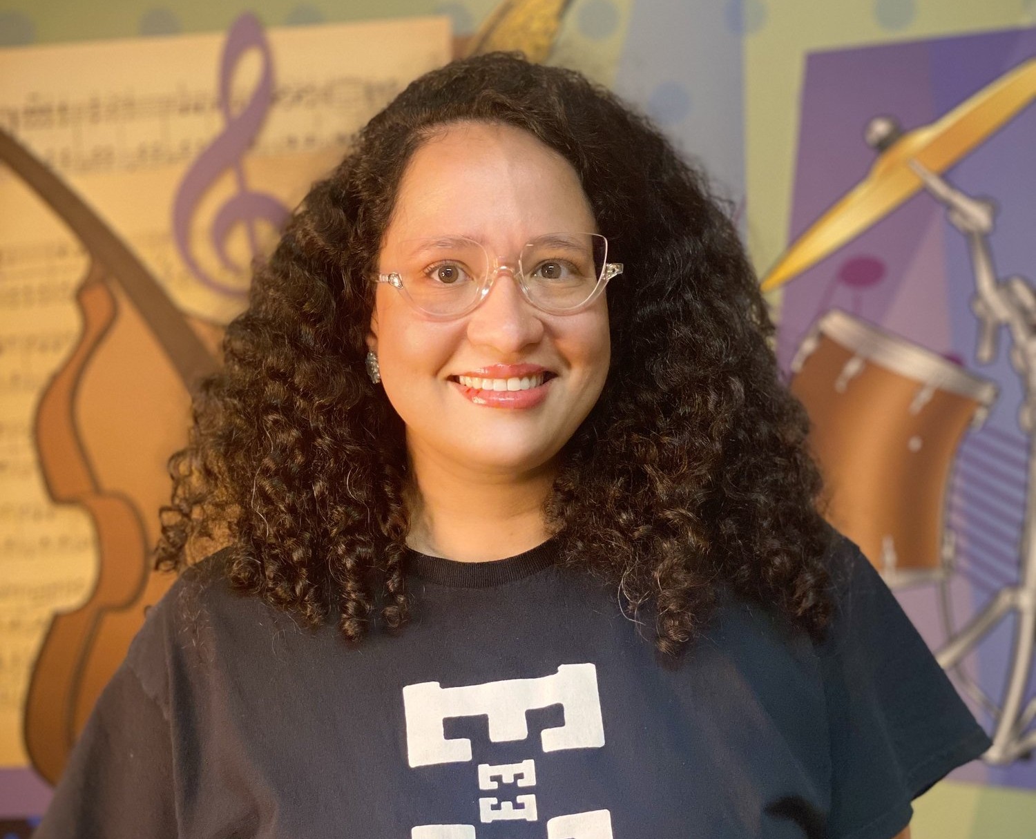 Lais Santos smiling in front of a colorful music mural
