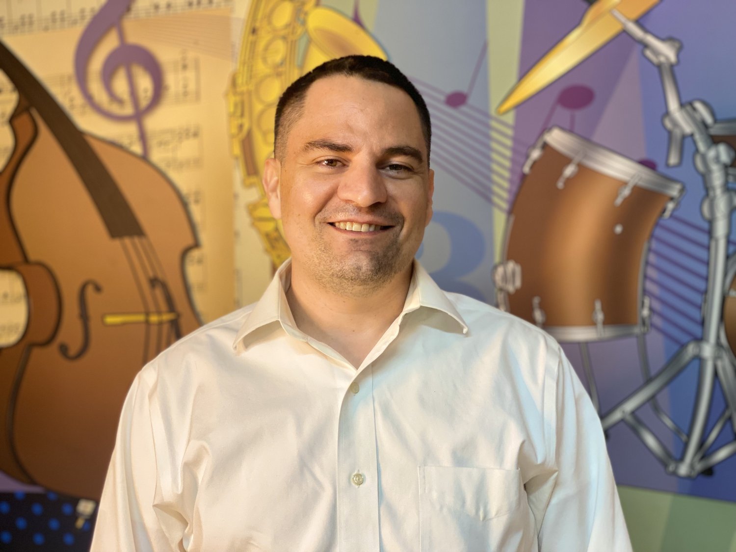 Music teacher Stephen Armada in front of musical instruments mural