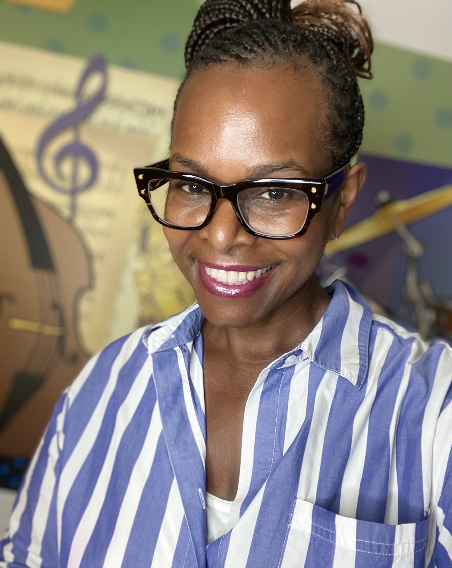 Una-Kariim Cross smiling in front of a music-themed mural