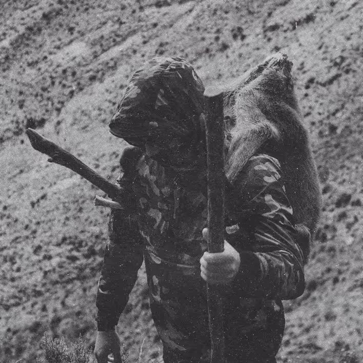 image of a man hiking with a deer on his back