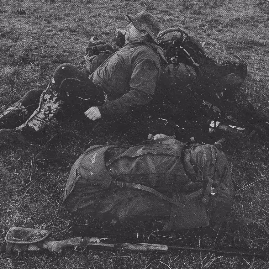 a man reclining on camping gear in a field